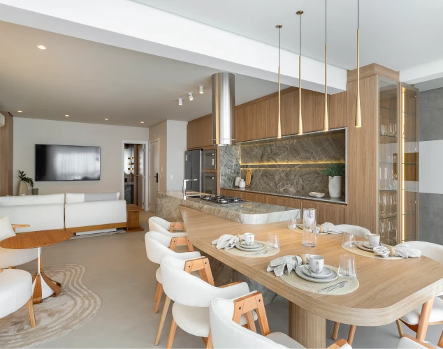 Living integrado do apartamento do Tremezzo, com bancada de mármore e mesa de jantar